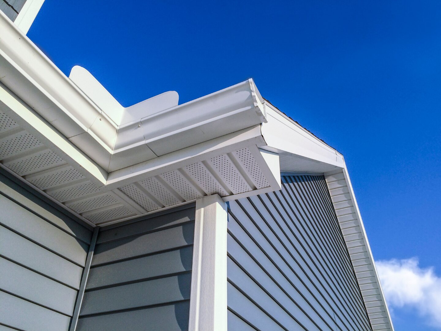 White gutter, fascia and bargeboard detail against a deep blue sky