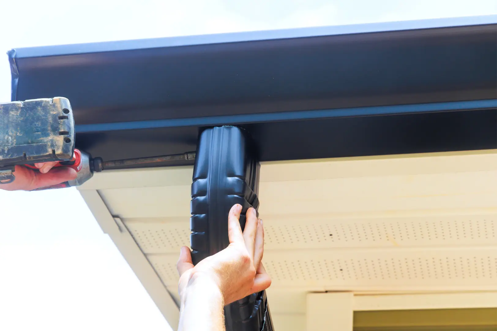 Dark downpipe being secured beneath a residential gutter