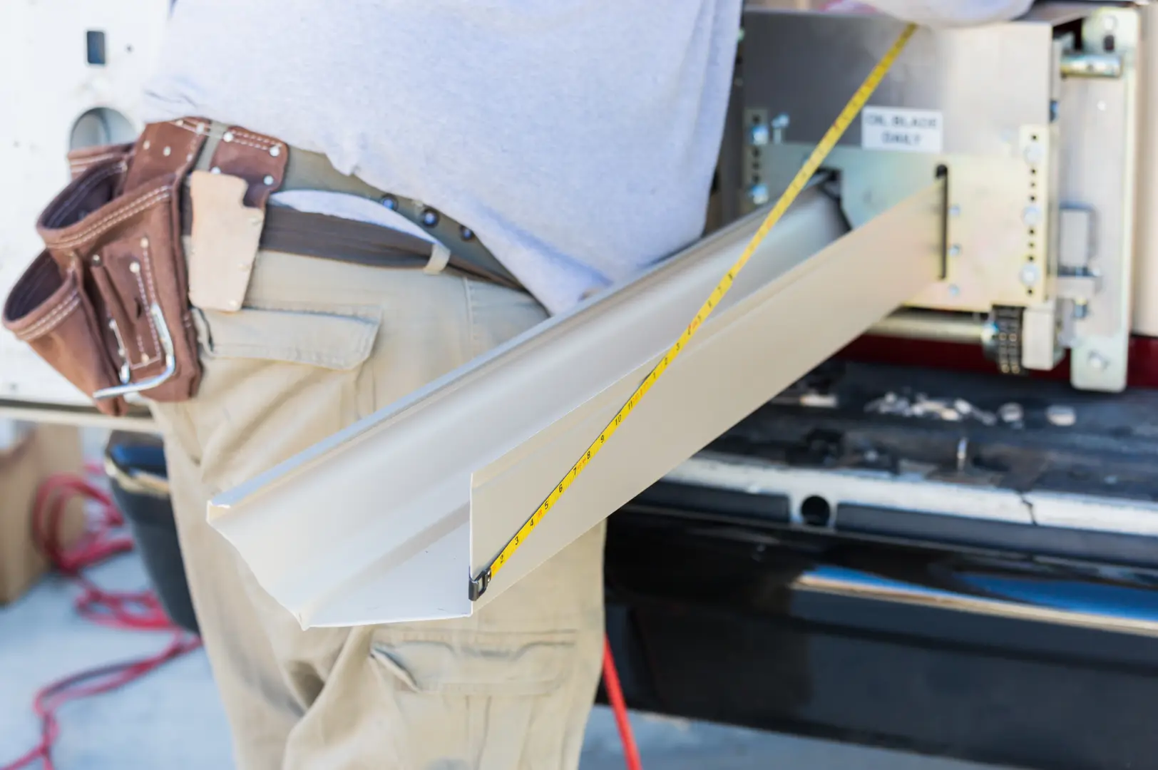 Installer measuring a newly formed seamless gutter