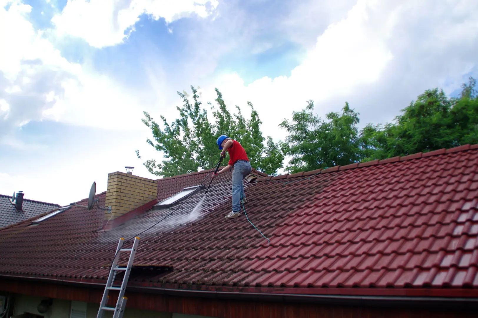 Professional pressure washing a large tiled roof
