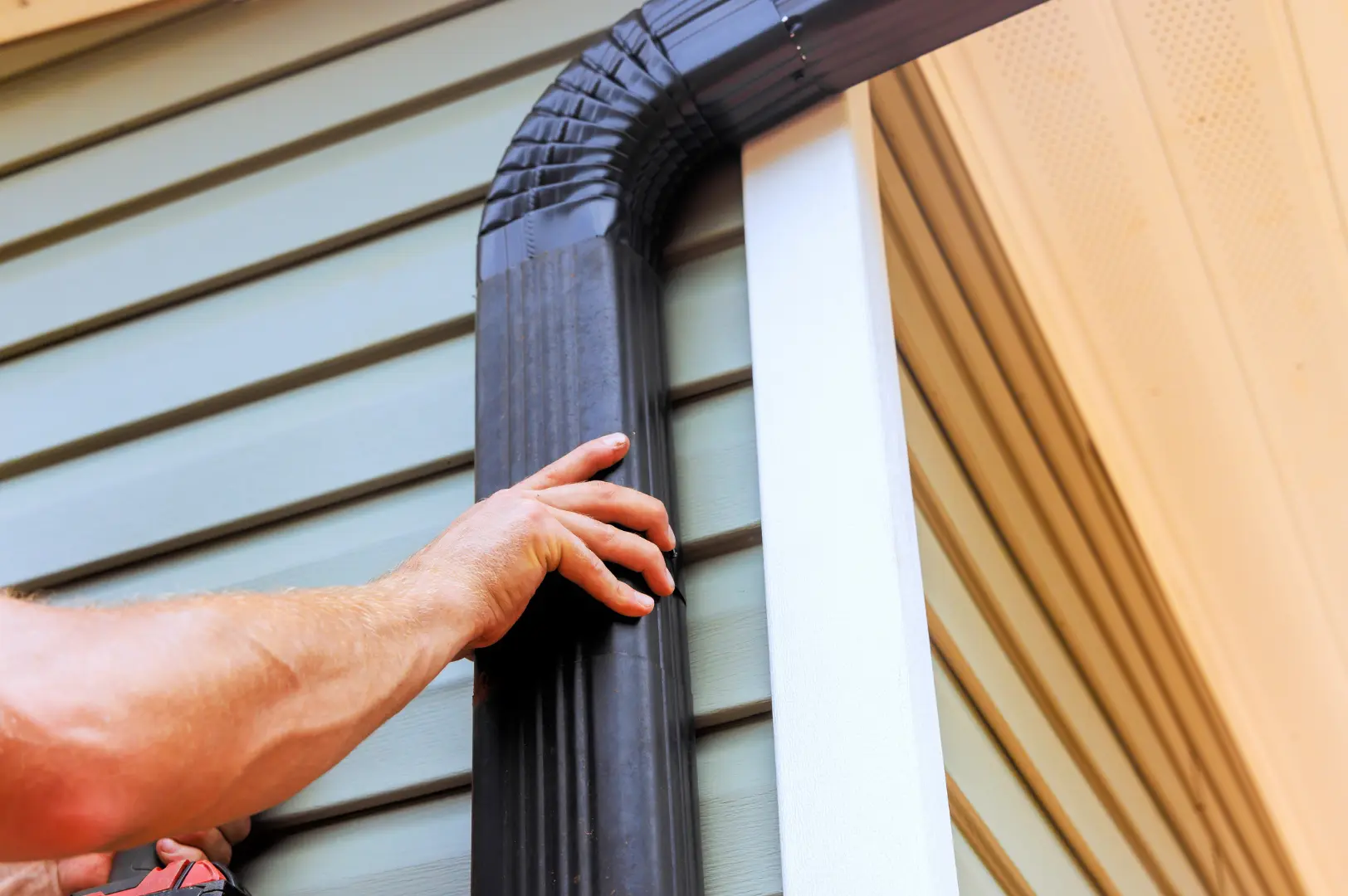 Installer positioning a dark downpipe beside a window